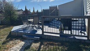 Une terrasse avec des meubles d’extérieur, une petite piscine et une plateforme en bois.