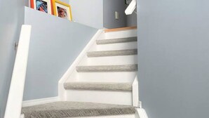 Un escalier avec des marches blanches et un mur gris.