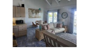 Ein Wohnzimmer mit einer Couch, einem Esstisch und einer Küchenzeile mit einer Mikrowelle.
