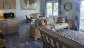 A living room with a sofa, a dining table, and a kitchen area with a microwave.
