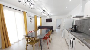 Una cocina moderna con comedor, lavadora y televisor de pantalla plana.