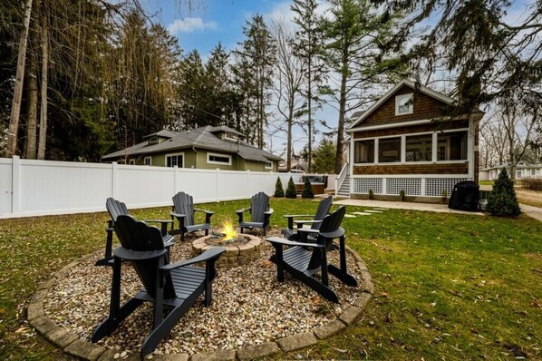 Ein Garten mit Feuerstelle und Adirondack-Stühlen.
