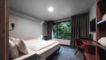 Una habitación de hotel moderna con una cama grande, un escritorio, una silla y un televisor.