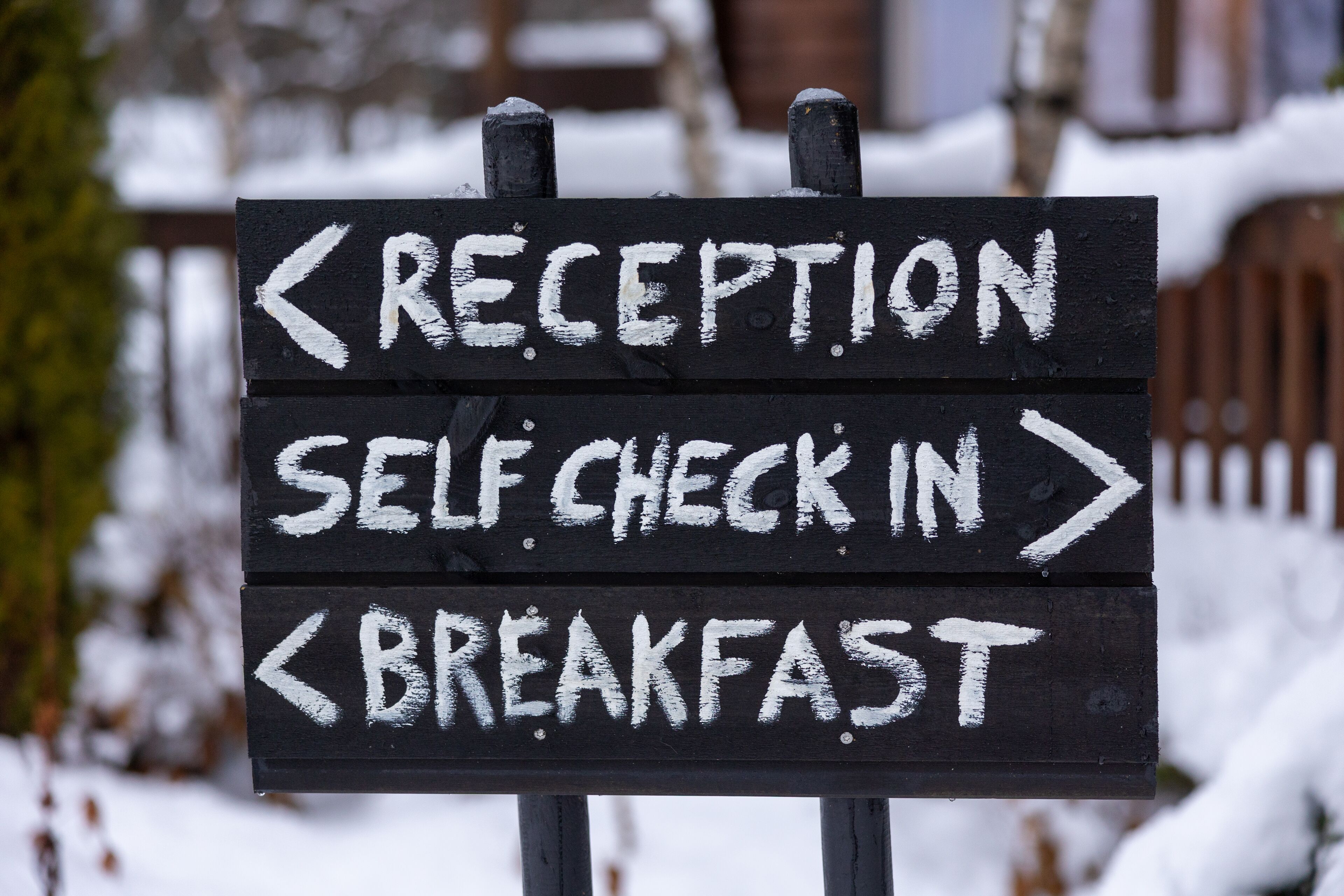 Señal direccional con flechas indicando recepción, auto-registro y desayuno.