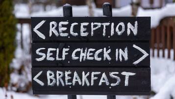 Señal direccional con flechas indicando recepción, auto-registro y desayuno.