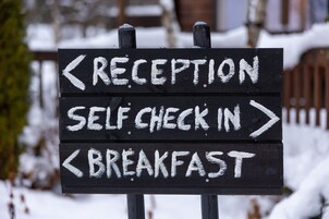 Señal direccional con flechas indicando recepción, auto-registro y desayuno.