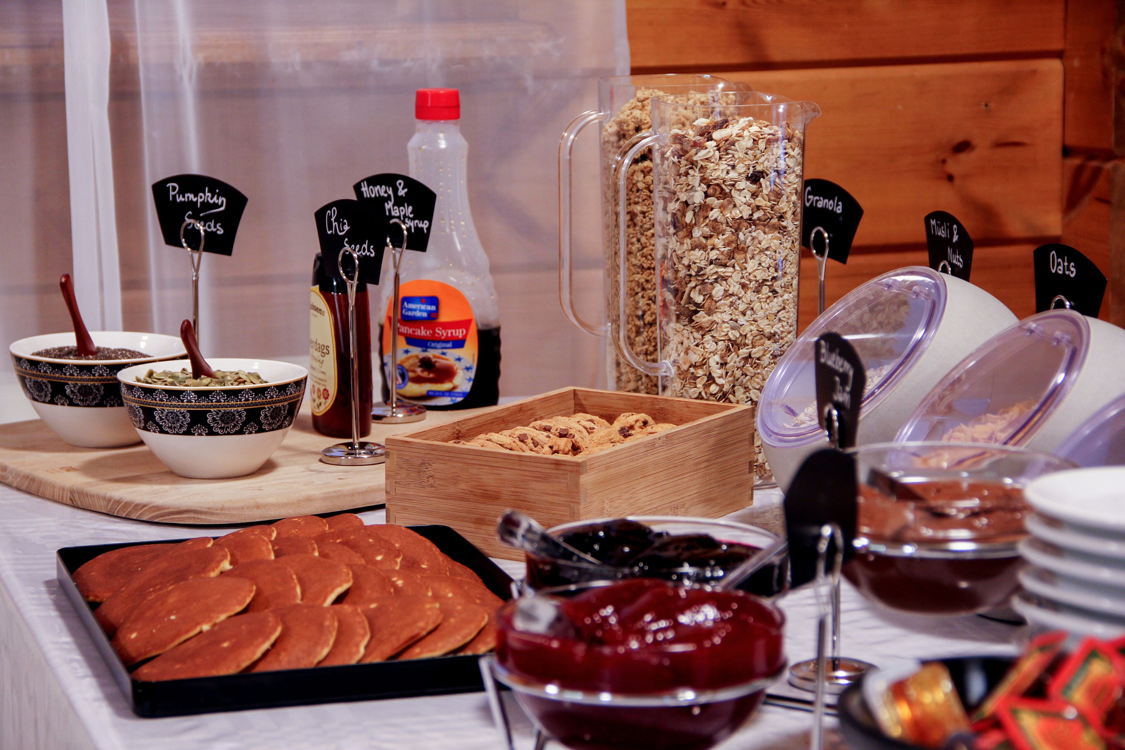 Ein reichhaltiges Buffet mit verschiedenen Speisen und Beilagen, darunter Pfannkuchen, Granola und Ahornsirup.