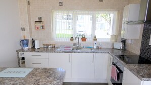 A modern kitchen with granite countertops, white cabinets, a built-in oven, and a window with blinds. - Sleeps6- Countryside Privacy- 30mintobeach (Gunnislake)