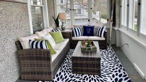 Une véranda accueillante avec un coin salon confortable, une petite table et une plante en pot.