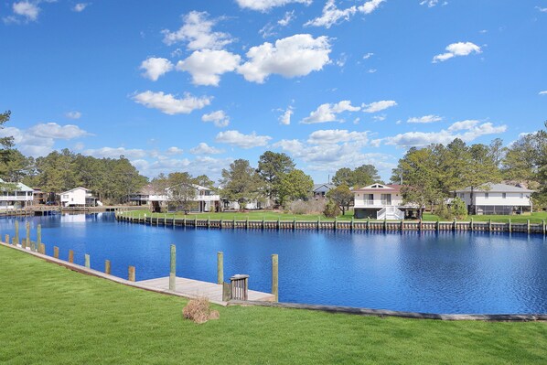 A calm lake with a dock, surrounded by houses and greenery.