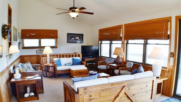 A cozy living room with a wooden sofa, a television, and a ceiling fan. - Charming, well maintained contemporary home with every attention to detail. (Duck)