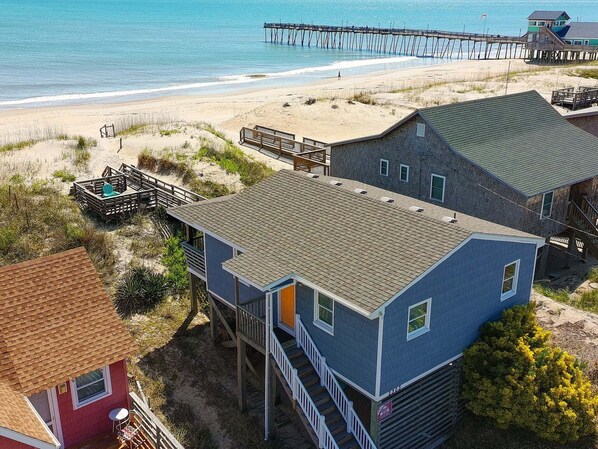 A coastal house with a beach view, a pier, and a small dock.