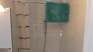 Ein kleines Badezimmer mit Waschbecken, Toilette und Dusche, alles in Weiß.