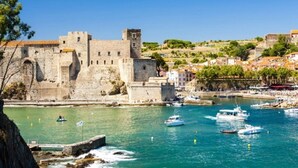 A historic stone castle by a harbor with boats and a clear blue sky. - Loue Mobilhome (Sérignan)
