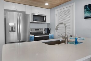 Enjoy cooking in this well-equipped kitchen with a refrigerator, microwave, and stove, along with a large sink and modern faucet.