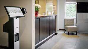 A reception area with a self-service kiosk, a cushioned chair, and a large window. - Fortune Hotel Huddersfield M62 JCT24, Sure Collection by Best Western (Huddersfield)