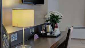 A hotel reception desk with a lamp, a vase of flowers, a tray with a coffee pot and cups, and a television mounted on the wall. - Fortune Hotel Huddersfield M62 JCT24, Sure Collection by Best Western (Huddersfield)