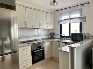 Une cuisine moderne dotée d’appareils électroménagers en acier inoxydable, de meubles blancs et d’un plan de travail en granit.