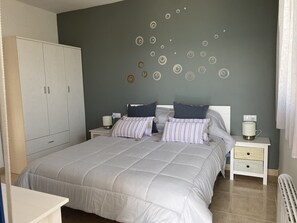 Une chambre à coucher avec un grand lit, deux tables de chevet, une armoire et un mur orné de motifs circulaires.