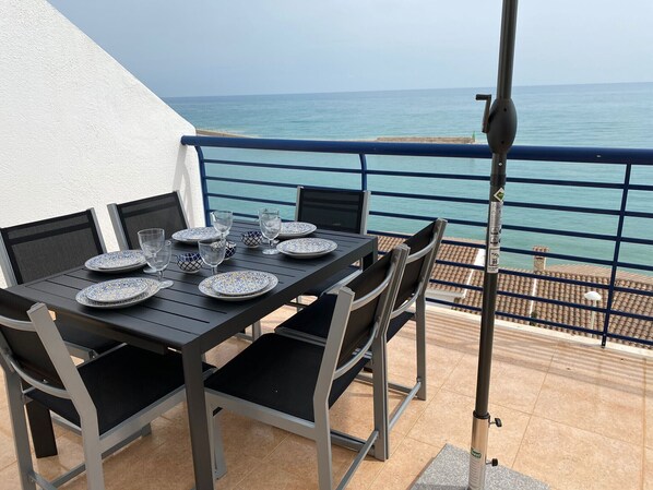 Un balcon avec une table dressée pour le dîner, donnant sur la mer.