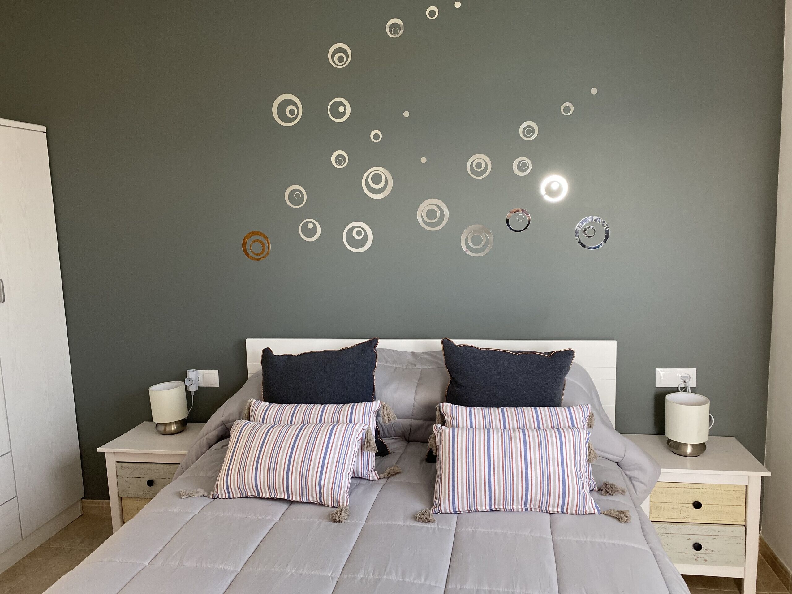 A bedroom with a bed, two nightstands, and a wall with circular decorations.