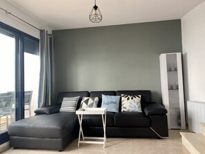 Un soggiorno moderno con un divano grigio, un tavolino bianco e una lampada a sospensione geometrica.