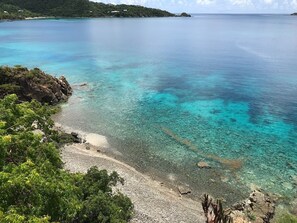 Een uitzicht op de kust met helder turquoise water, een rotsachtige kustlijn en weelderige begroeiing.