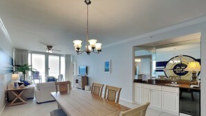 A modern hotel room with a dining area, kitchen, and a balcony with a view.