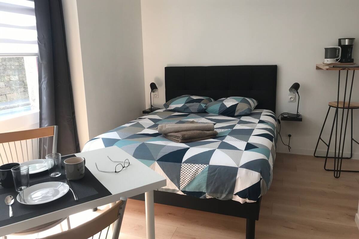 A neatly arranged bedroom with a bed, bedside tables, a chair, and a table with breakfast items.