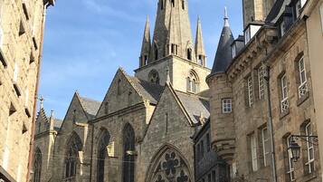 Een historisch kerkgebouw met een hoge spits en gotische architectuur, omringd door gebouwen van steen.