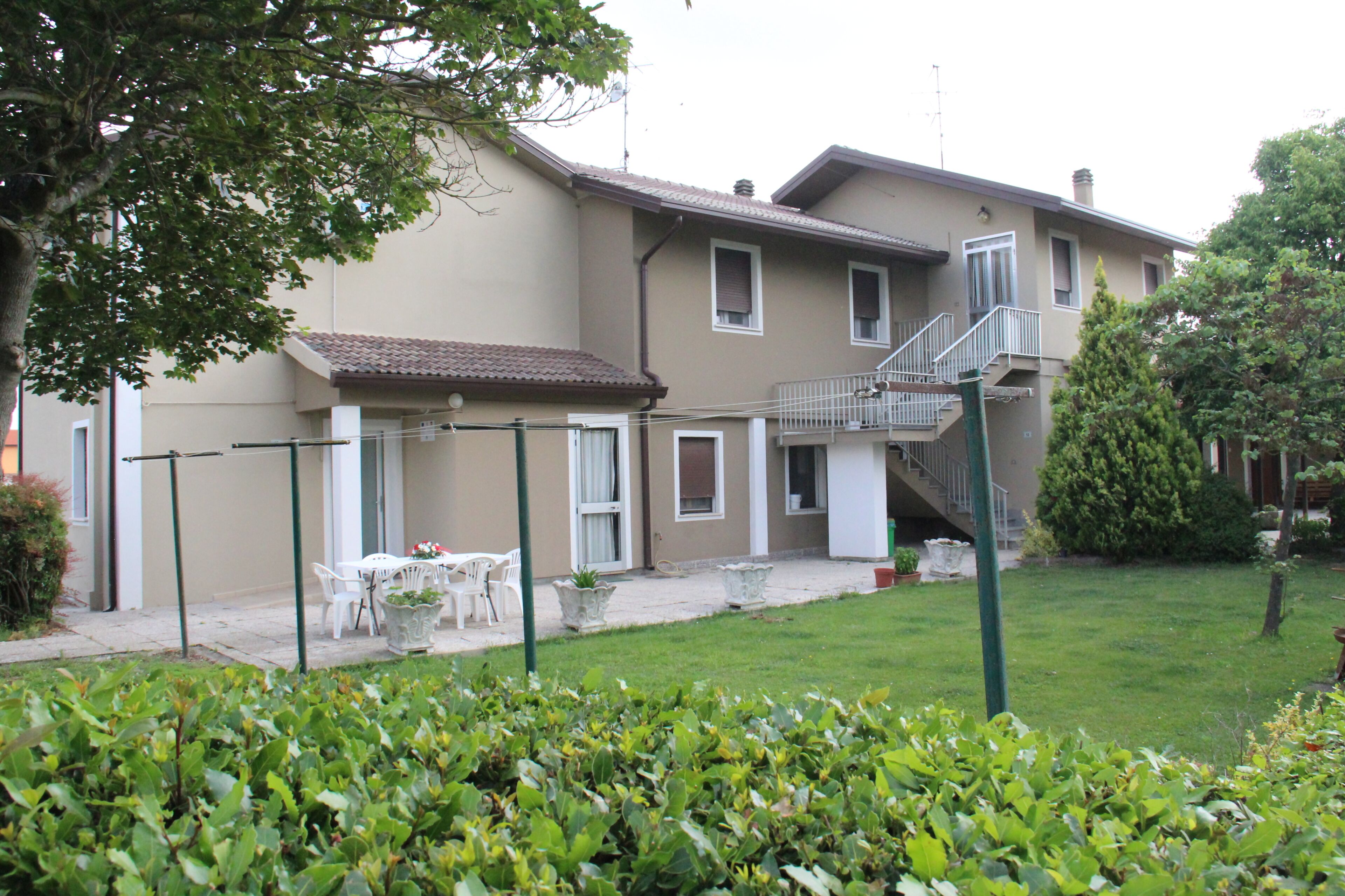 A residential building with a patio area, outdoor furniture, and a staircase leading to an upper floor.