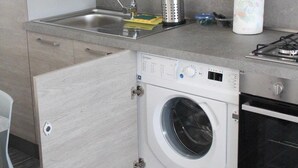 Una cocina compacta con lavadora integrada, un lavabo y una estufa.