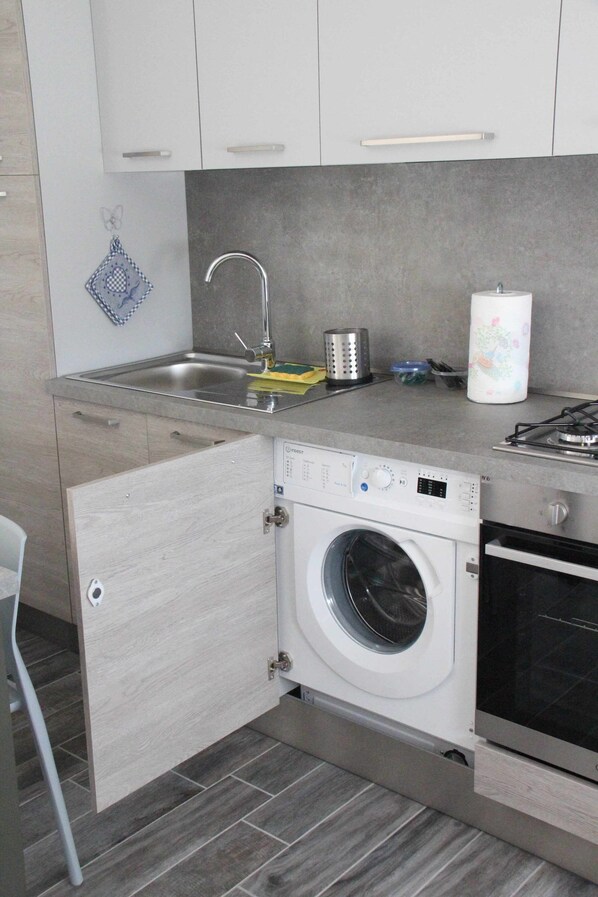 A compact kitchen with a built-in washing machine, a sink, and a stove.