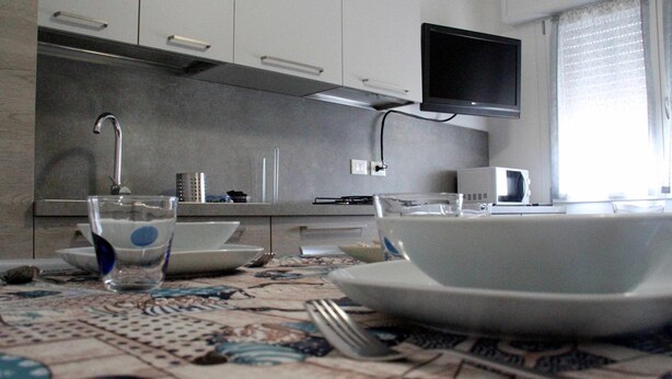 Una cocina moderna con televisor de pantalla plana, microondas y pileta.