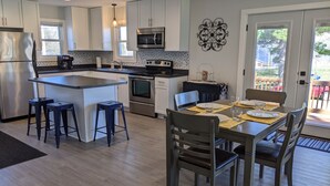 Een moderne keuken met witte kastjes, roestvrijstalen apparatuur en een centraal eiland met barstoelen.