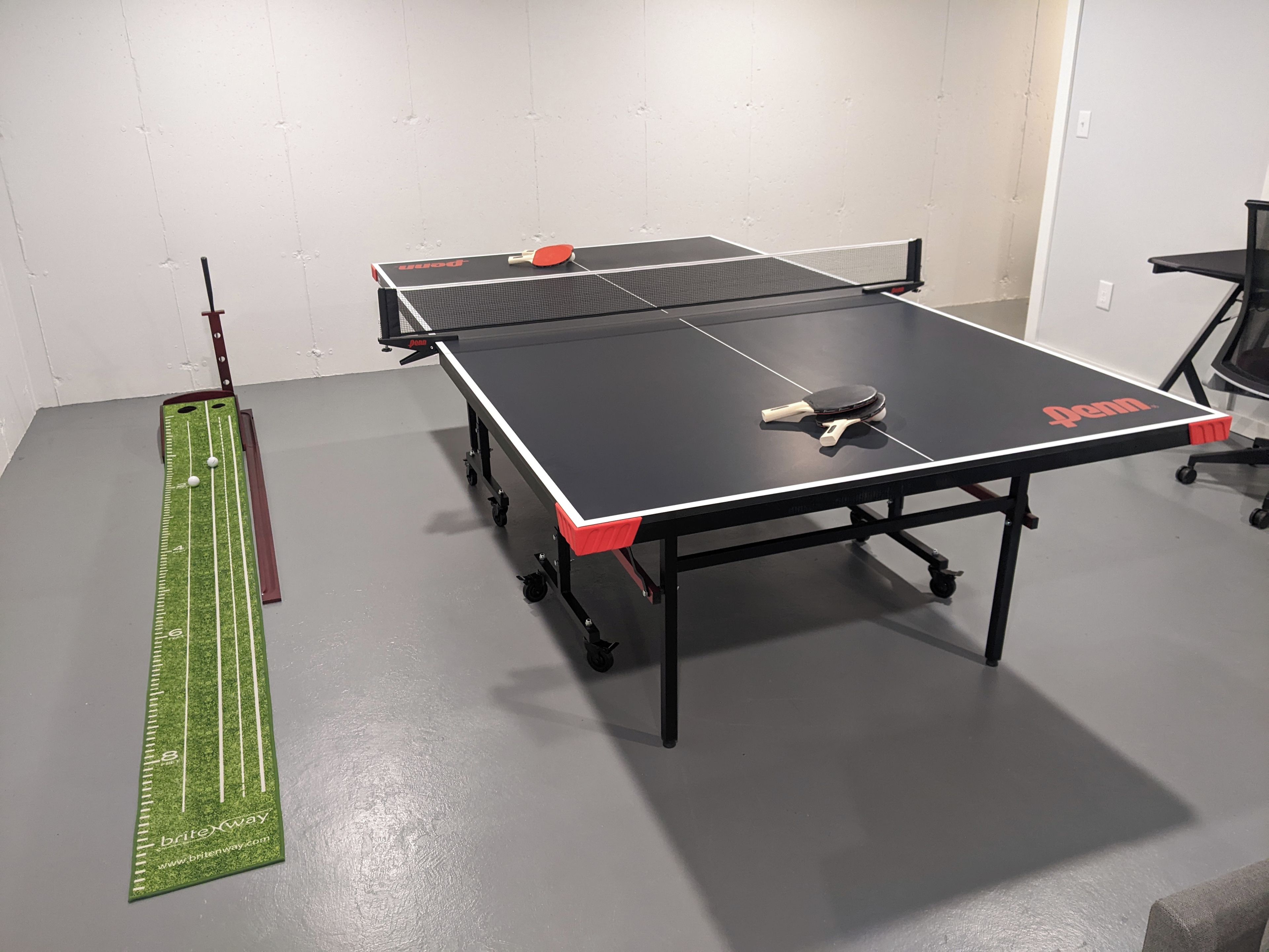 Une table de ping-pong avec un filet, une raquette de tennis de table et un mètre ruban.