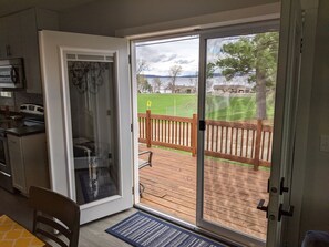 A kitchen with a sliding glass door leading to a wooden deck with a view of a grassy field and a lake. - Updated home with lake views, across the street from Lake WI, near free ferry (Merrimac)