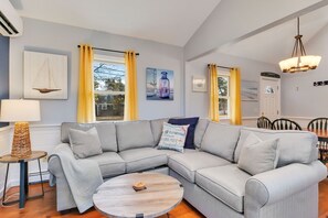 A modern living room with a grey sectional sofa, a round coffee table, and yellow curtains.