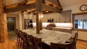 Una cocina amplia con una isla grande, vigas de madera y electrodomésticos modernos.