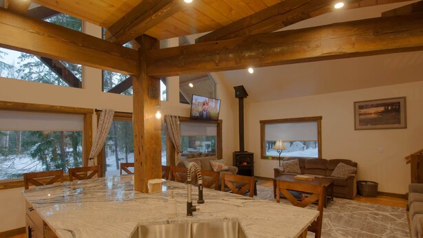 Una cocina amplia con una isla grande, vigas de madera y una chimenea.