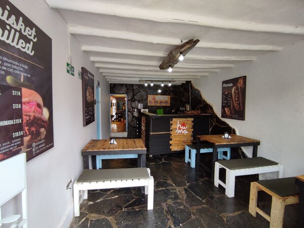 A restaurant interior with a stone wall, wooden tables, and benches.