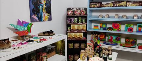 A room with shelves stocked with snacks, a table with a cake, and various items on a counter.