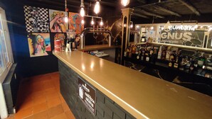 Uma área de bar com balcão, diversos frascos e obras de arte nas paredes.