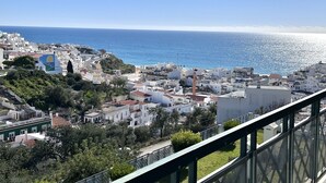 Paisagem costeira urbana com edifícios, um farol imponente e o mar.