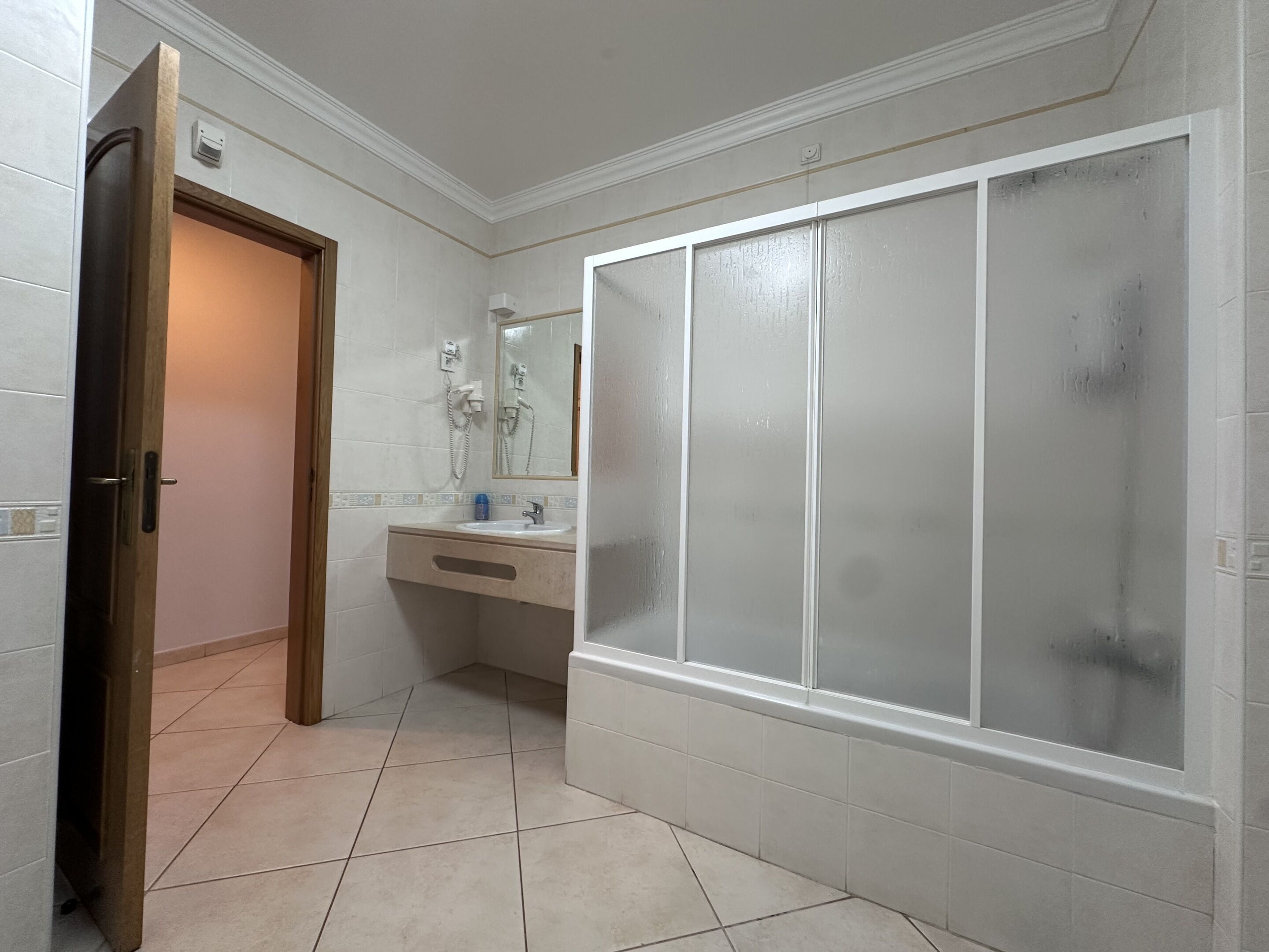 A bathroom with a shower, a sink, and a mirror.