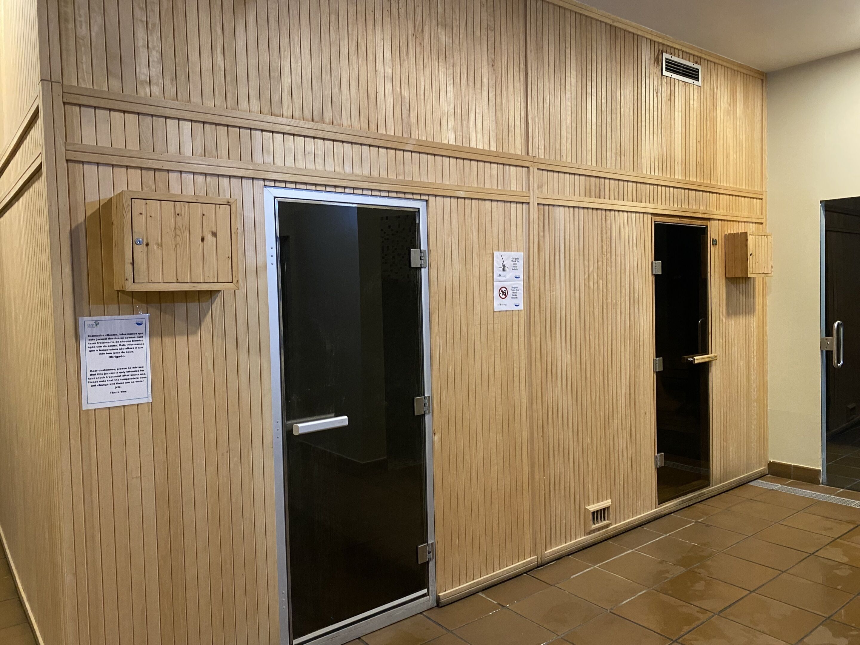 A hallway with wooden paneling, a glass door, and a small wooden cabinet.