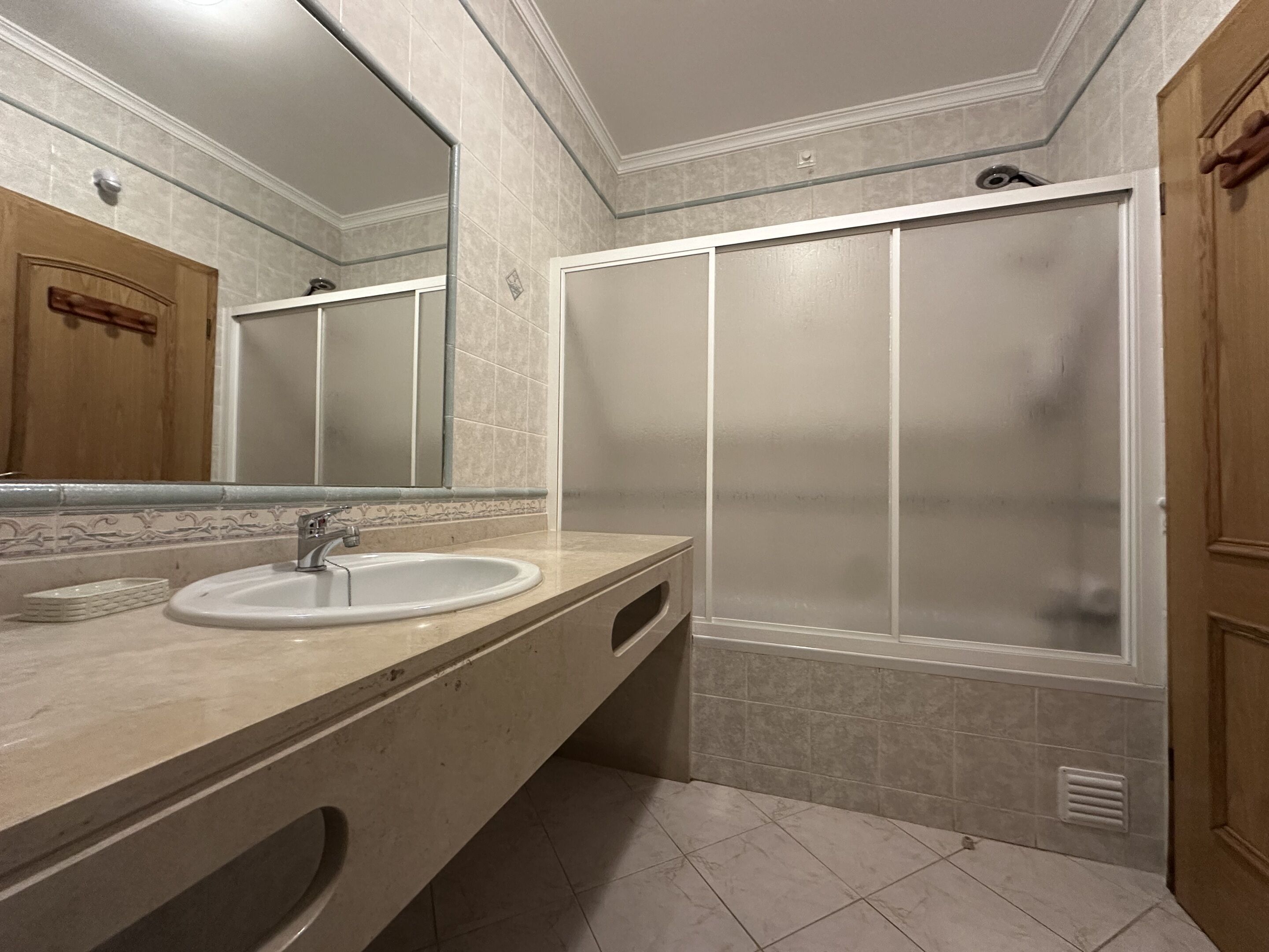 A bathroom with a sink, mirror, and a shower enclosure.
