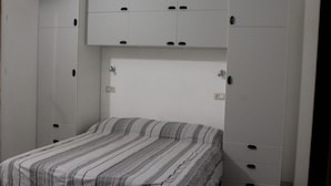 A bedroom with a bed, white cabinets, and a white headboard. - Camera MINERVA (Pisa)