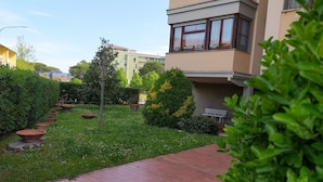 A courtyard with a paved walkway, potted plants, and a bench. - Camera MINERVA (Pisa)