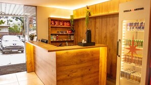 A reception area with a wooden counter, a vending machine, and a car parked outside. - Hotel Montana by Bsb Inn (Nucleo Bandeirante)